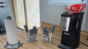A kitchen with a wooden countertop, a coffee maker, knife holders, and a roll of paper towels.