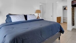 A bedroom with a bed, a nightstand, a lamp, and a closet.