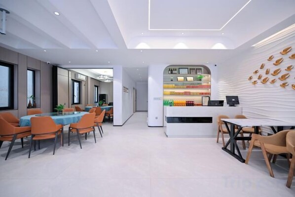 A modern interior with a dining area, a counter with beverages, and a wall with a leaf pattern.