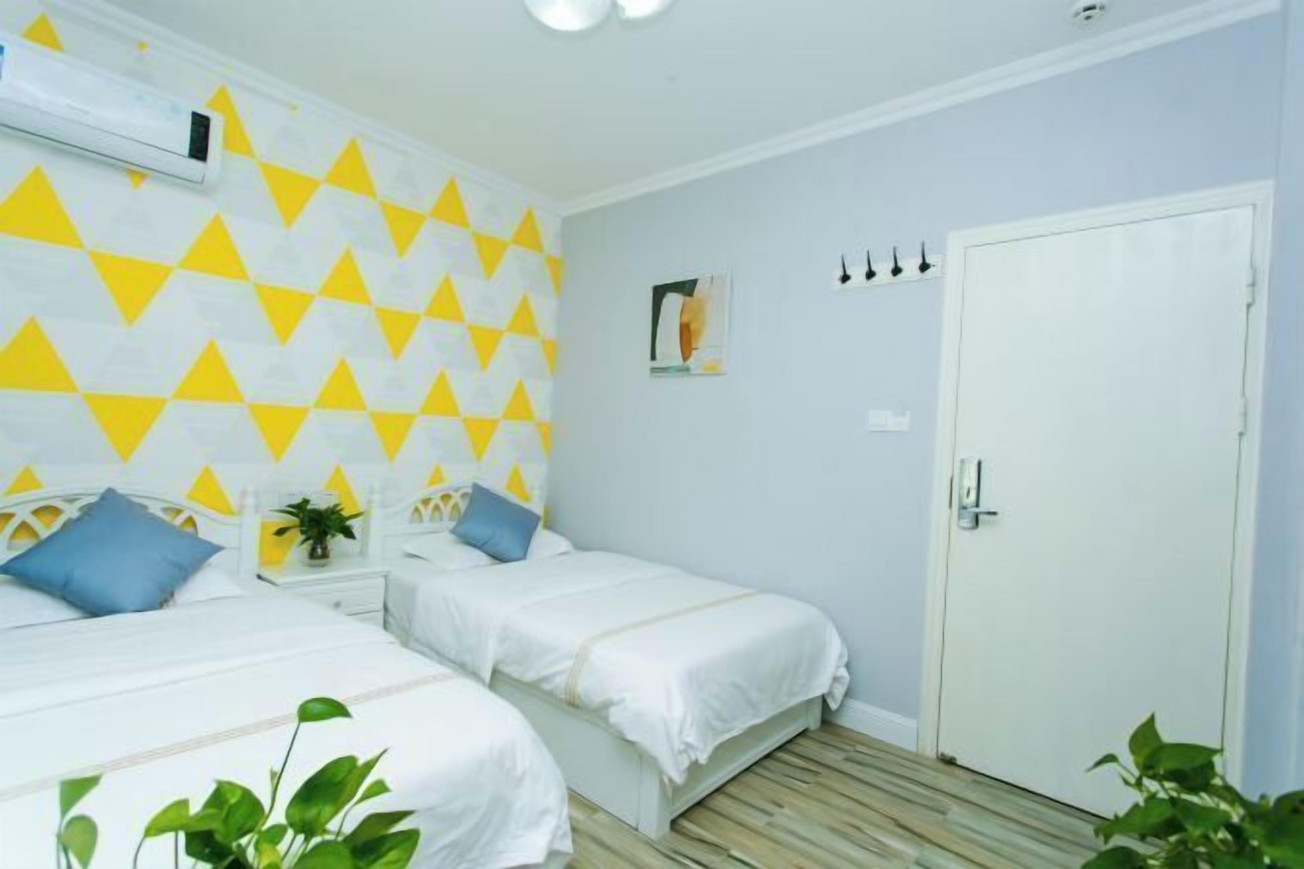 A room with two beds, a white door, and a geometric-patterned wall.