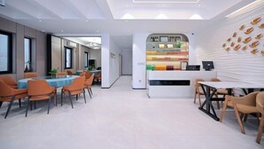 A modern hotel lobby with a reception desk, seating area, and a wall with decorative elements. - Aiqinhai Hotel (Shengsi)