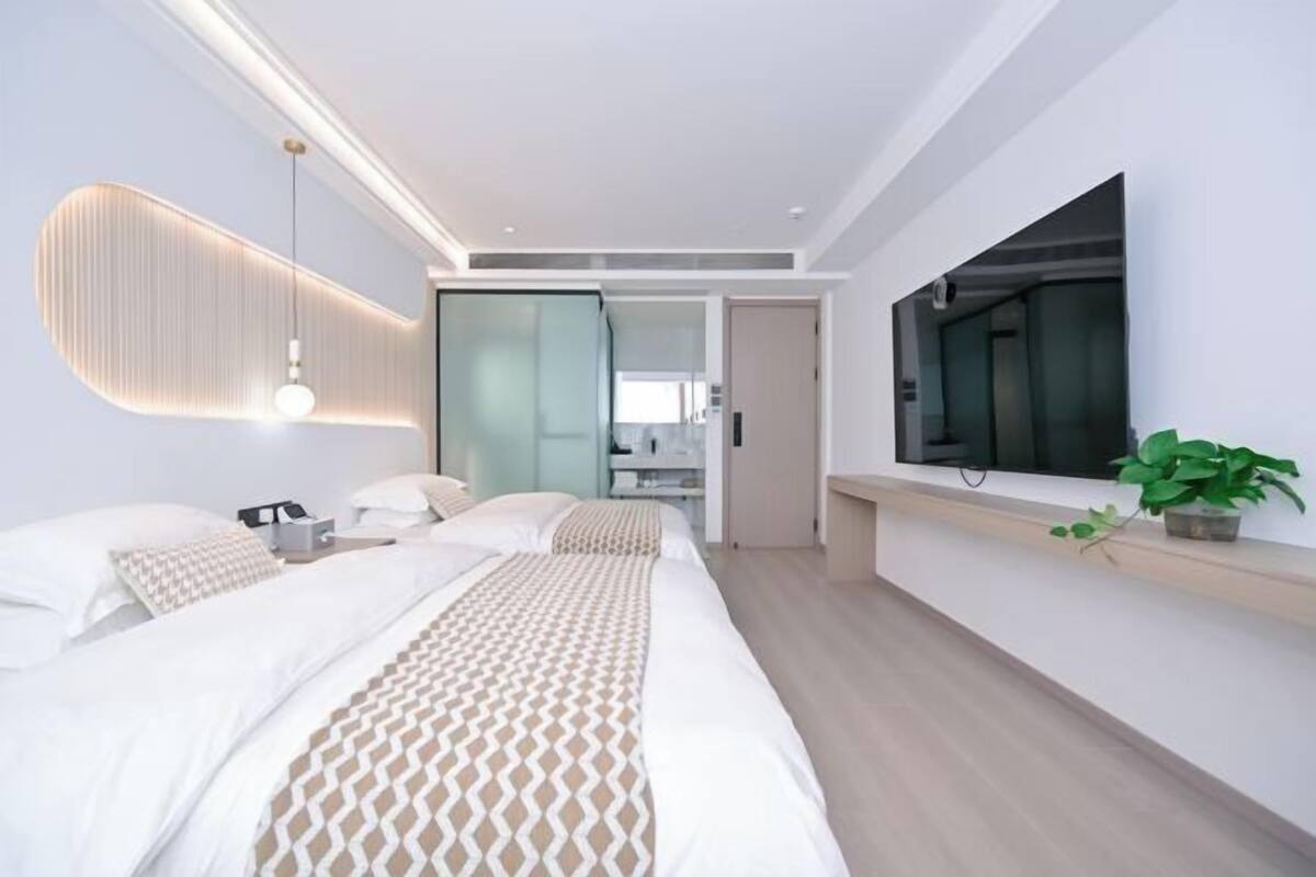 Una habitación de hotel moderna con una cama grande, televisión de pantalla plana, mesita de noche y un ventanal amplio.