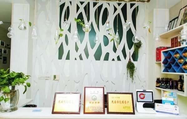 A reception area with a white decorative partition, framed certificates on a counter, and a digital kiosk.