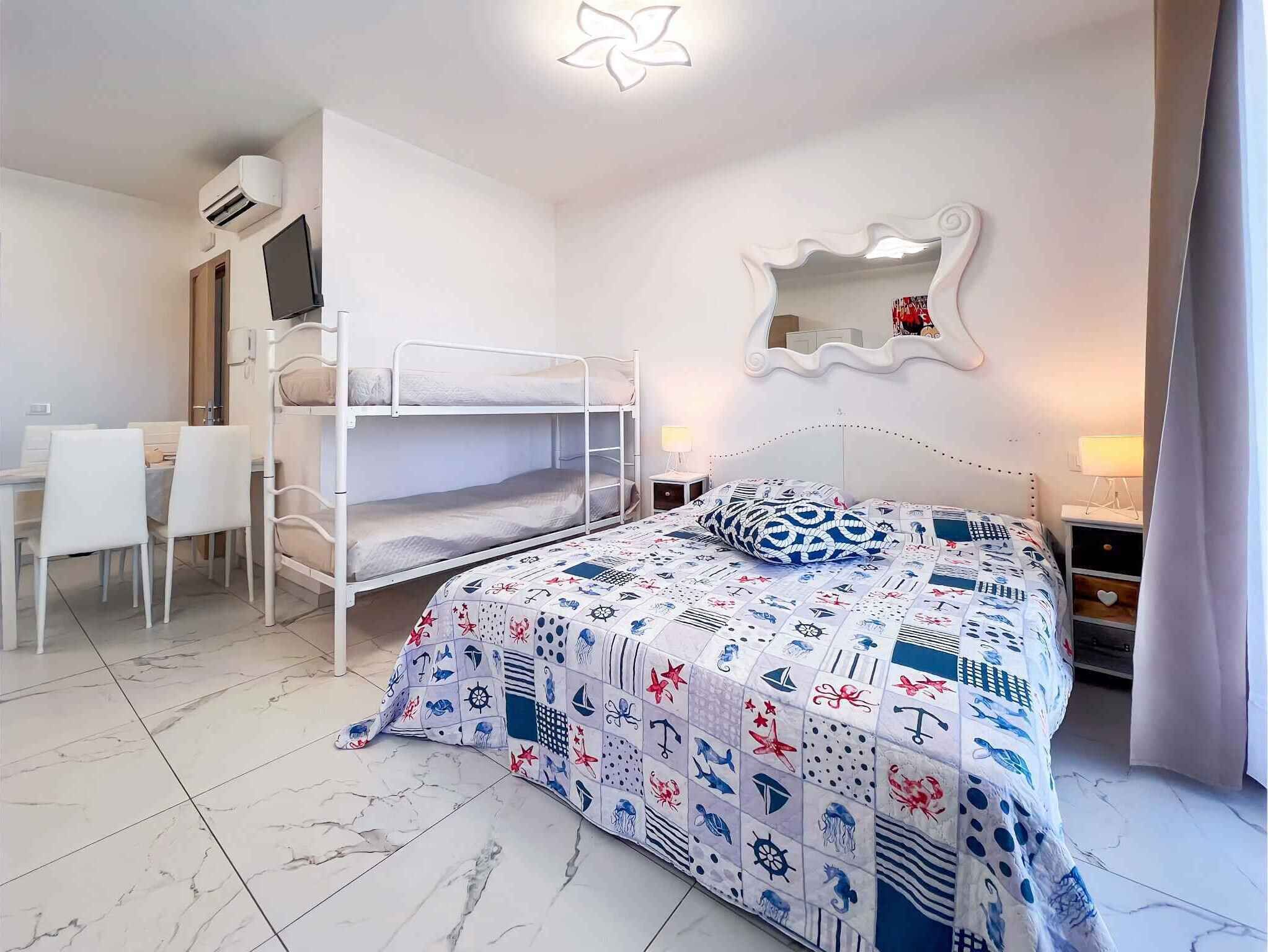 A bedroom with bunk beds, a desk, and a mirror.