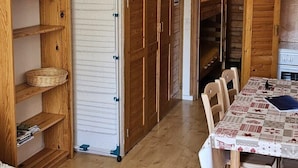 A room with a wooden floor, a bed, a dining table with chairs, wooden cabinets, and a radiator. - 1st floor, swimming pool, balcony, tv, ski locker, 32m², Valloire (Valloire)