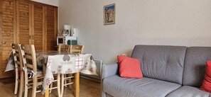 A dining area with a table set for four, a grey sofa, and a wall-mounted coffee maker.
