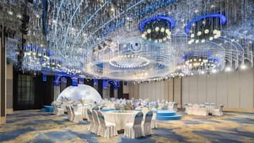 Une salle de banquet avec des tables rondes, des chaises et un plafond décoratif.