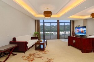 Habitación de hotel moderna con sofá, mesa de centro, televisión y vistas al exterior.