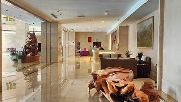 A modern lobby with a polished floor, a reception desk, and a large abstract sculpture.