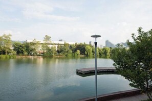 A serene lake with a dock, surrounded by greenery and modern buildings in the background. - Oriental Hotel (Kaihua Linhu Road) (Kaihua)
