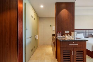 A hotel room with a bed, a small kitchenette, a wooden wardrobe, and a bathroom with a toilet and sink. - Oriental Hotel (Kaihua Linhu Road) (Kaihua)