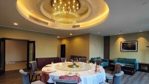 Un comedor con una mesa redonda, sillas y una araña.