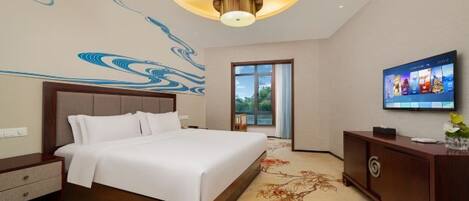 A hotel room with a large bed, a television, a desk, and a decorative wall mural.
