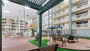 A multi-level atrium with a central seating area, a staircase, and a view of the building's exterior balconies. - Island Sunrise HHI Condo (Hilton Head Island)