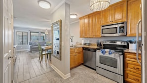 A modern kitchen with wooden cabinets, stainless steel appliances, and a chandelier. - Island Sunrise HHI Condo (Hilton Head Island)