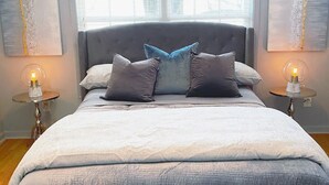 Un dormitorio con una cama grande, dos mesitas de noche con lámparas y dos obras de arte abstracto en la pared.