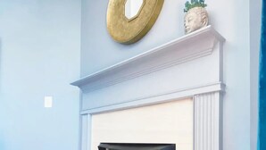 Una habitación con chimenea blanca, pared azul y suelo de madera.