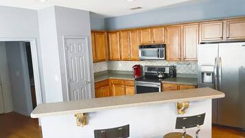 Een vaatwasser, een blender, kookgerei, borden en bestek, eettafels