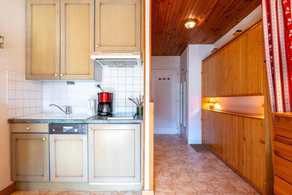 A kitchen with wooden cabinets, a dishwasher, and a coffee maker.
