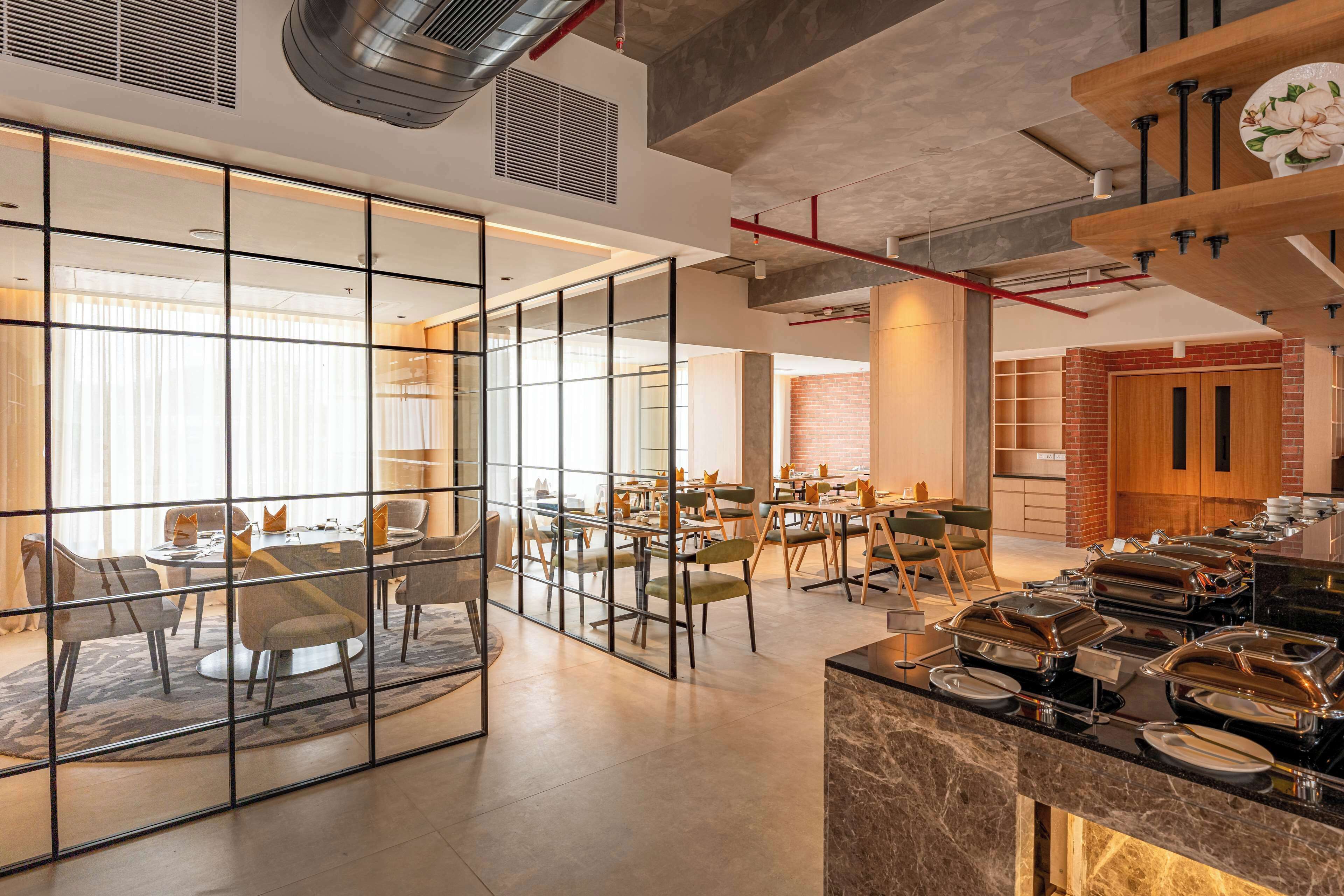 Un comedor moderno con divisiones de vidrio, un sistema de buffet y una pared de ladrillo decorativa.