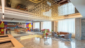 Un hall d’entrée spacieux avec un plafond haut, un coin cuisine moderne, des sièges confortables et un luminaire décoratif.