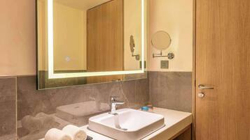 A modern bathroom with a large mirror, a sink, and a wooden door.