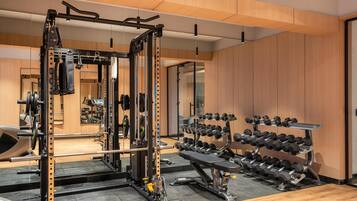 A gym with a squat rack, bench press, and various dumbbells.