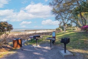 A picnic area with tables and benches, a charcoal grill, and a sign indicating 'Charcoal Ash Only'.