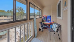 Un balcon doté de grandes fenêtres, d’un ventilateur de plafond et offrant une vue sur un immeuble dont le toit est végétalisé.