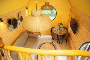 A wooden interior with a dining area, a large woven light fixture, and a round table with chairs. - Woodland Lodge, Aberporth (Brongest)