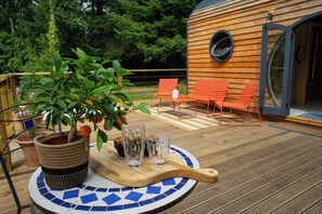 A wooden deck with a round table, potted plants, and outdoor seating. - Woodland Lodge, Aberporth (Brongest)