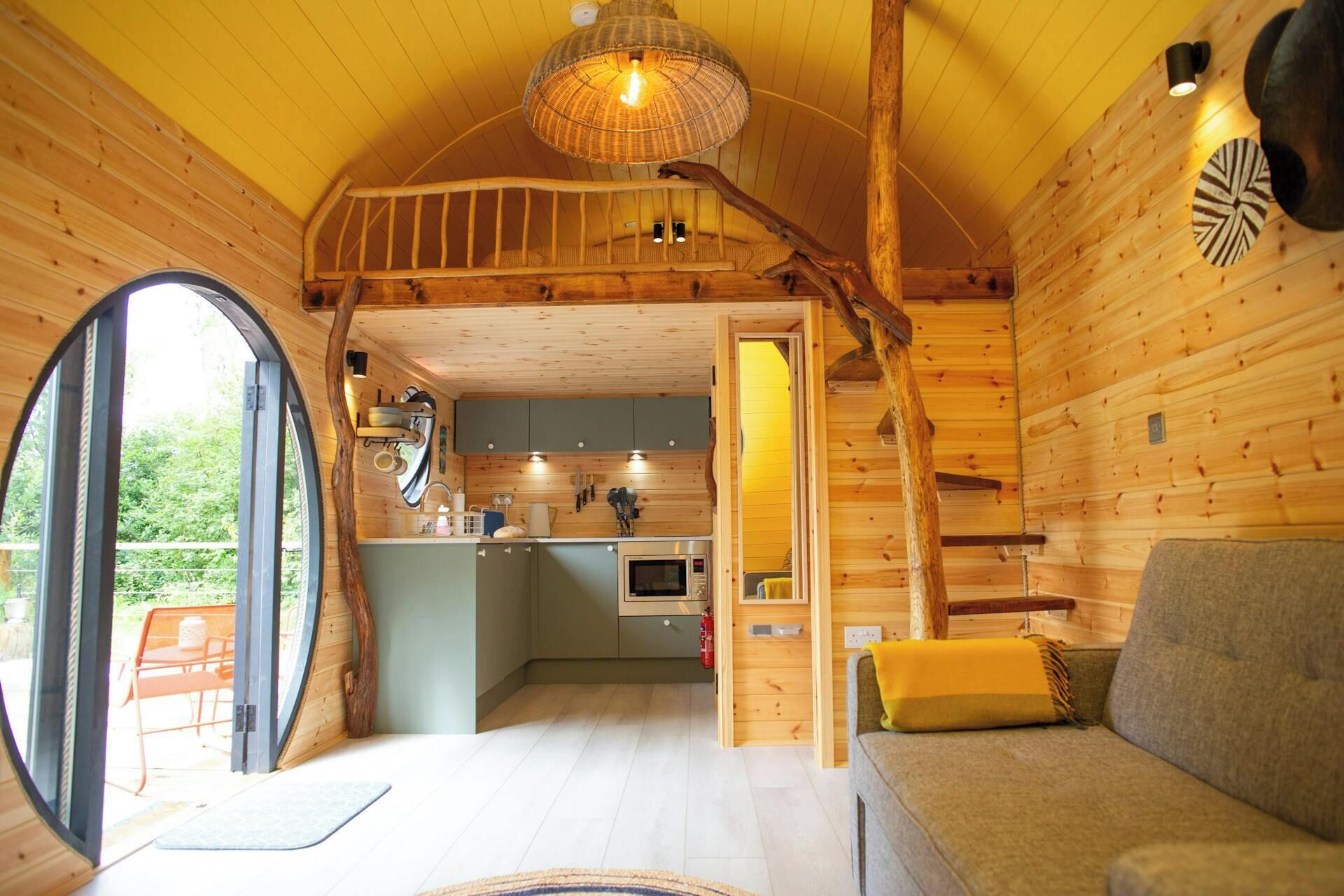 Interior acollidor d'una cabana amb zona de menjador, petita cuina i sofà.