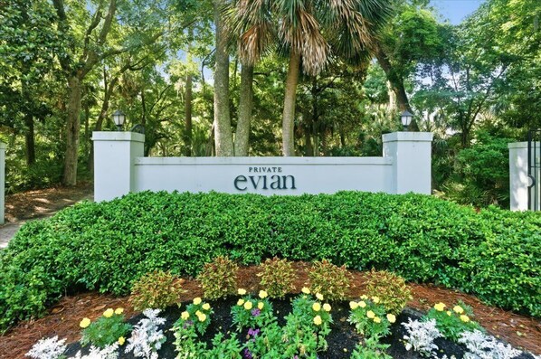 A private property entrance with a sign, lush greenery, and a well-maintained garden.