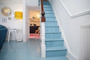A staircase with blue steps and white balusters, leading to a room with a pink floor.