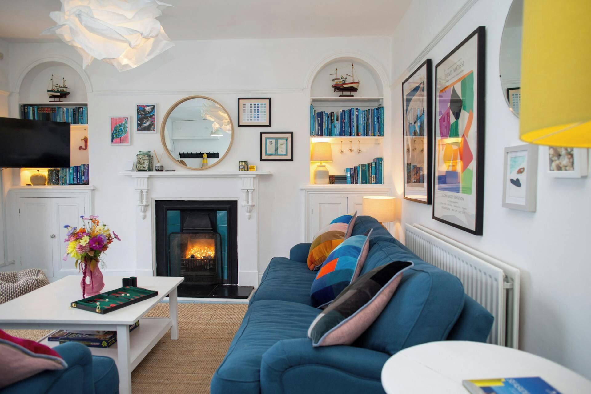 A living room with a fireplace, bookshelves, a sofa, and a television.