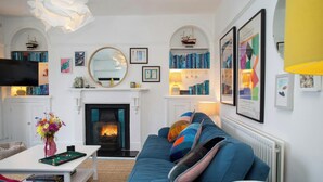 A living room with a fireplace, bookshelves, a sofa, and a television.