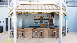 A bar with a wooden counter and stools, a chalkboard menu, and a sign prohibiting glass bottles in the pool area. - Aqua Vista Retreat - 2 BDR in Spectacular Resort! (Hilton Head Island)
