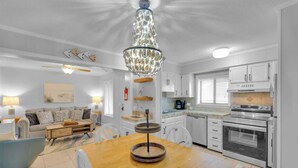 A modern kitchen with white cabinets, a built-in oven, and a dining area with a wooden table and chairs. - Aqua Vista Retreat - 2 BDR in Spectacular Resort! (Hilton Head Island)