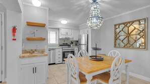 A modern kitchen with white cabinets, a wooden dining table, and a chandelier. - Aqua Vista Retreat - 2 BDR in Spectacular Resort! (Hilton Head Island)