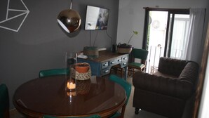 A dining area with a round wooden table, teal chairs, and a decorative centerpiece. - Charming 1-bedroom apartment with WiFi, AC in fabulous GFJ (GFJ)