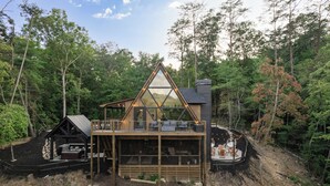 A cabin with a triangular roof, a deck, and a covered outdoor seating area. - Luxury A-Frame: Pets, Pickleball & Peloton w/Views (Mineral Bluff)