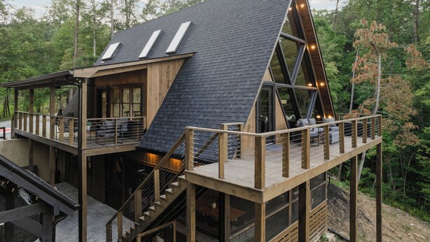 A modern, wooden cabin with a sloped roof, multiple decks, and outdoor seating areas. - Luxury A-Frame: Pets, Pickleball & Peloton w/Views (Mineral Bluff)