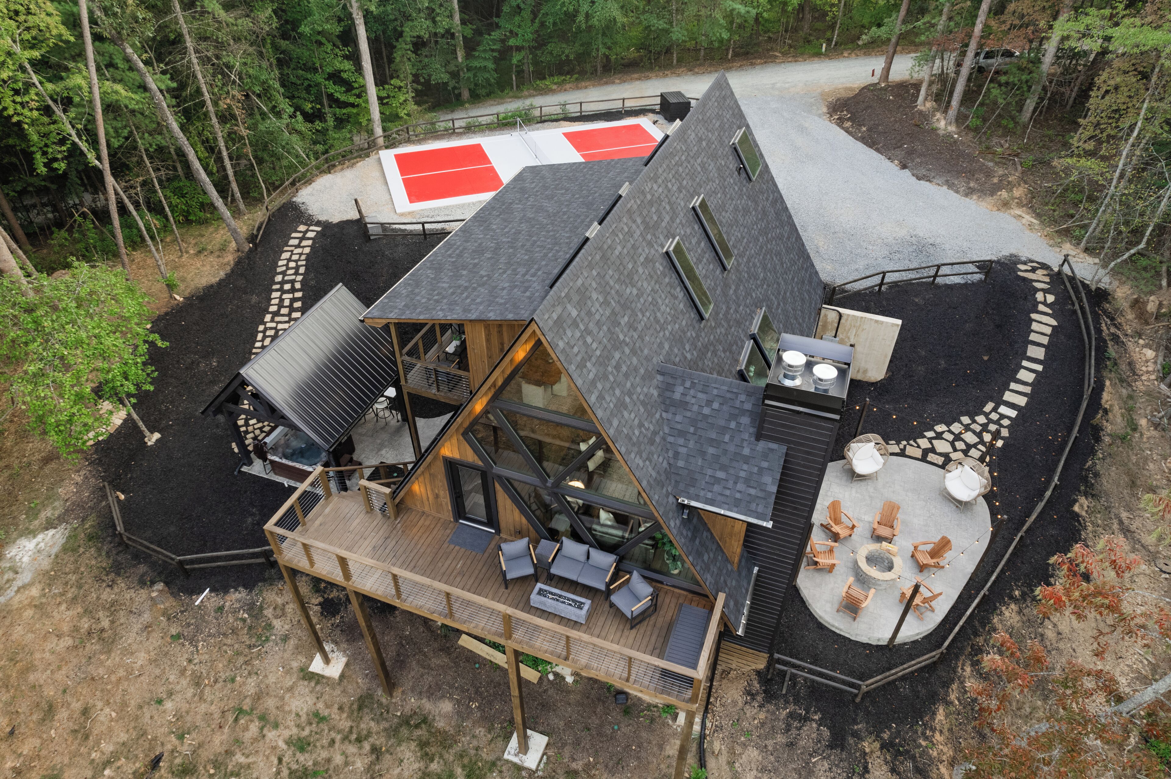 A modern cabin with a deck, outdoor seating area, and a fire pit.