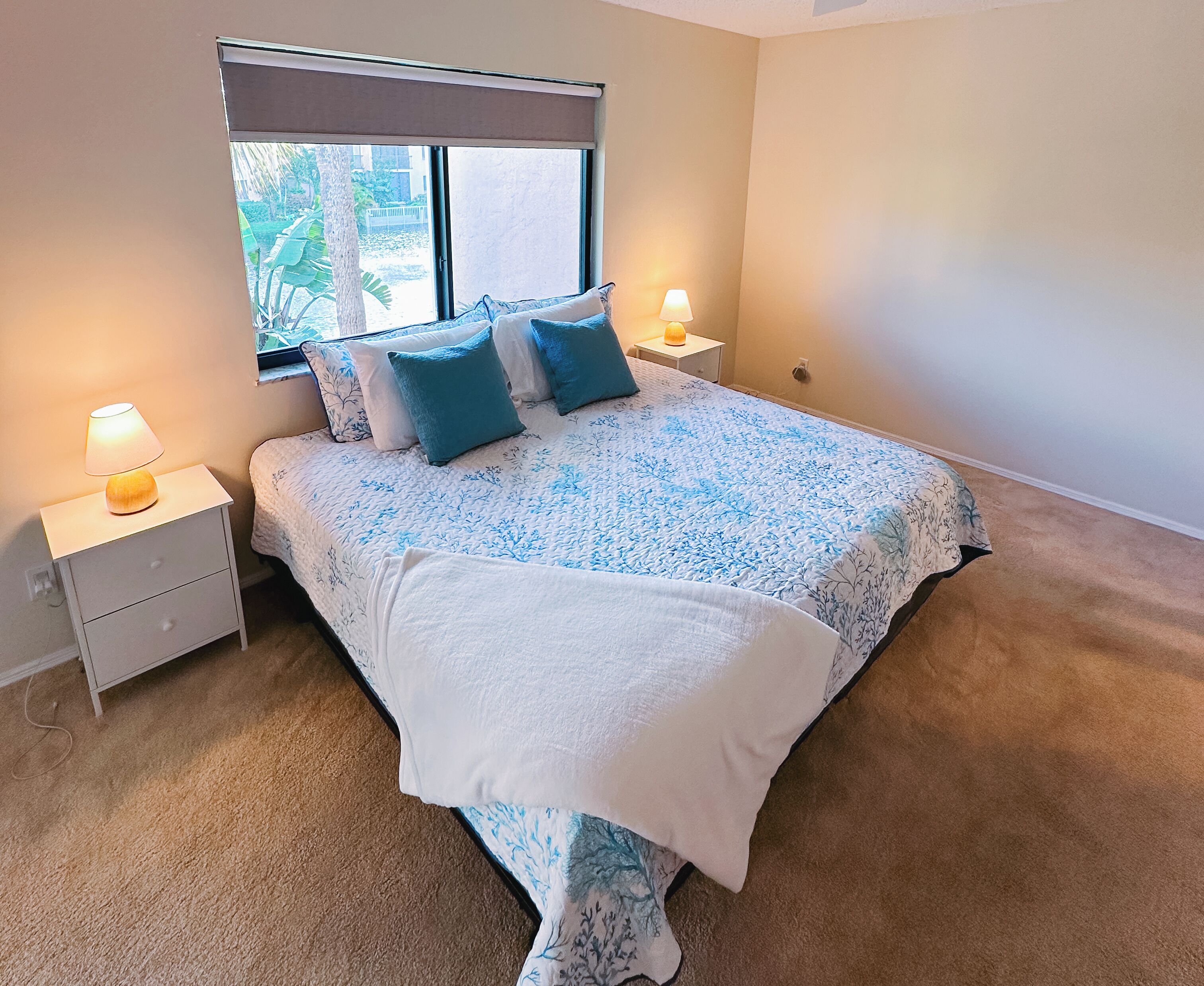 Une chambre à coucher avec un lit, deux tables de chevet, une fenêtre et une lampe.