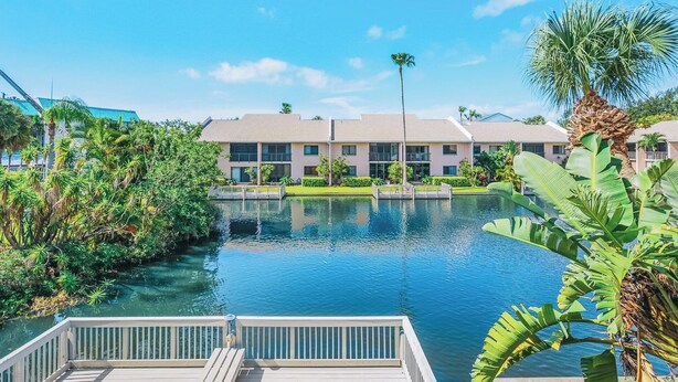 Un hotel amb una piscina envoltat de vegetació tropical i un cel blau clar.