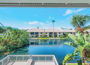 A hotel with a pool surrounded by tropical vegetation and a clear blue sky. - Lakefront Condo at Ocean Village (Fort Pierce)