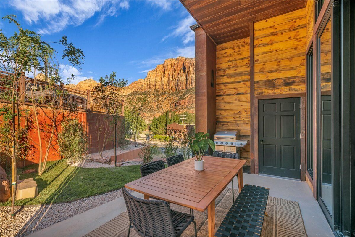 A wooden exterior with a patio area, a grill, and a view of red rock formations.