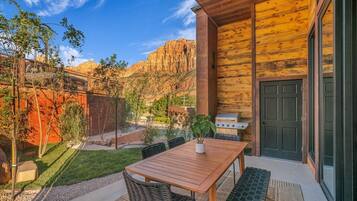 A wooden exterior with a patio area, a grill, and a view of red rock formations.