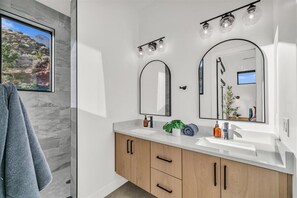 Enjoy a serene bathroom retreat with a large mirror, sink, and ample natural light.