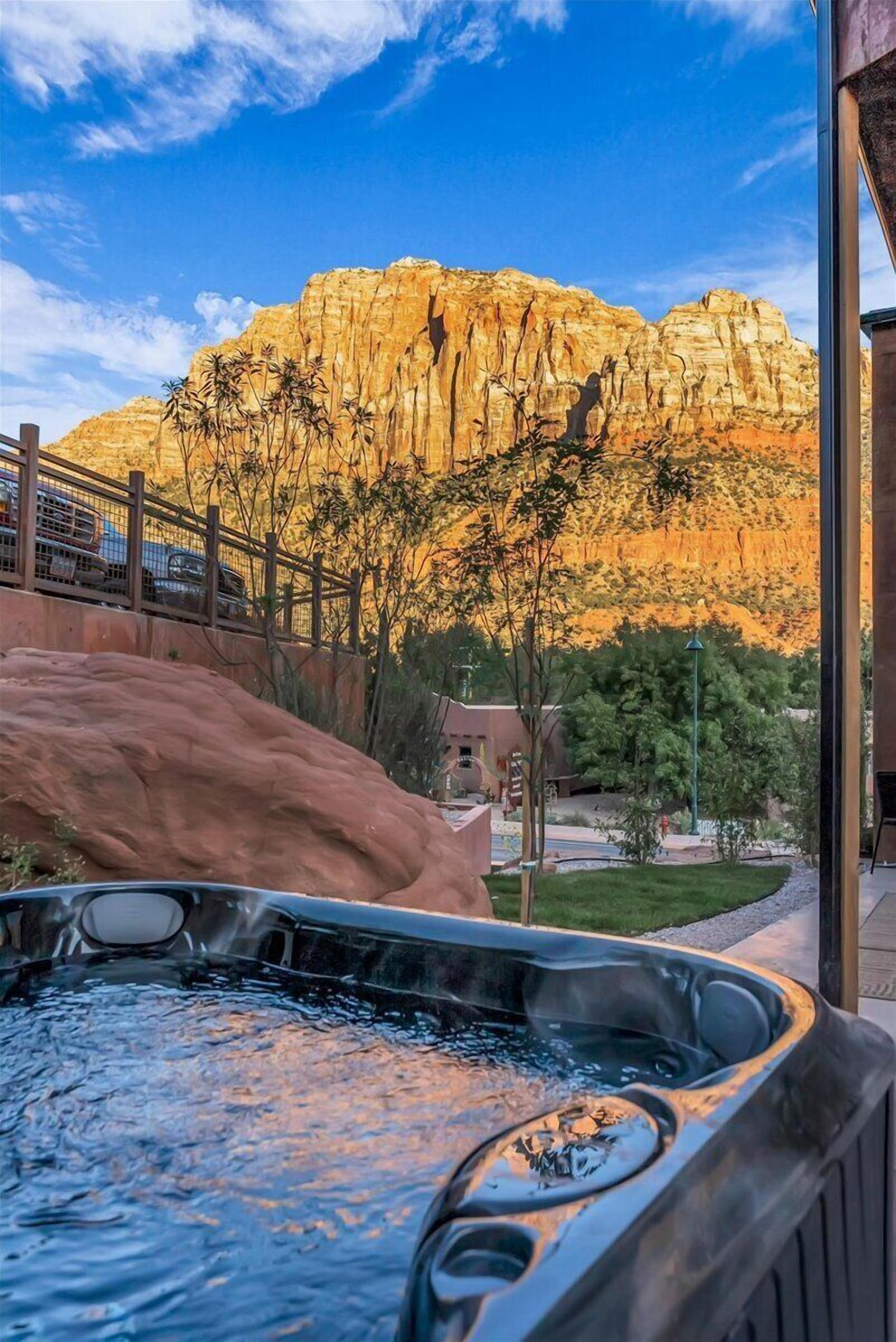 A hot tub with a view of a rocky mountain and a wooden fence.